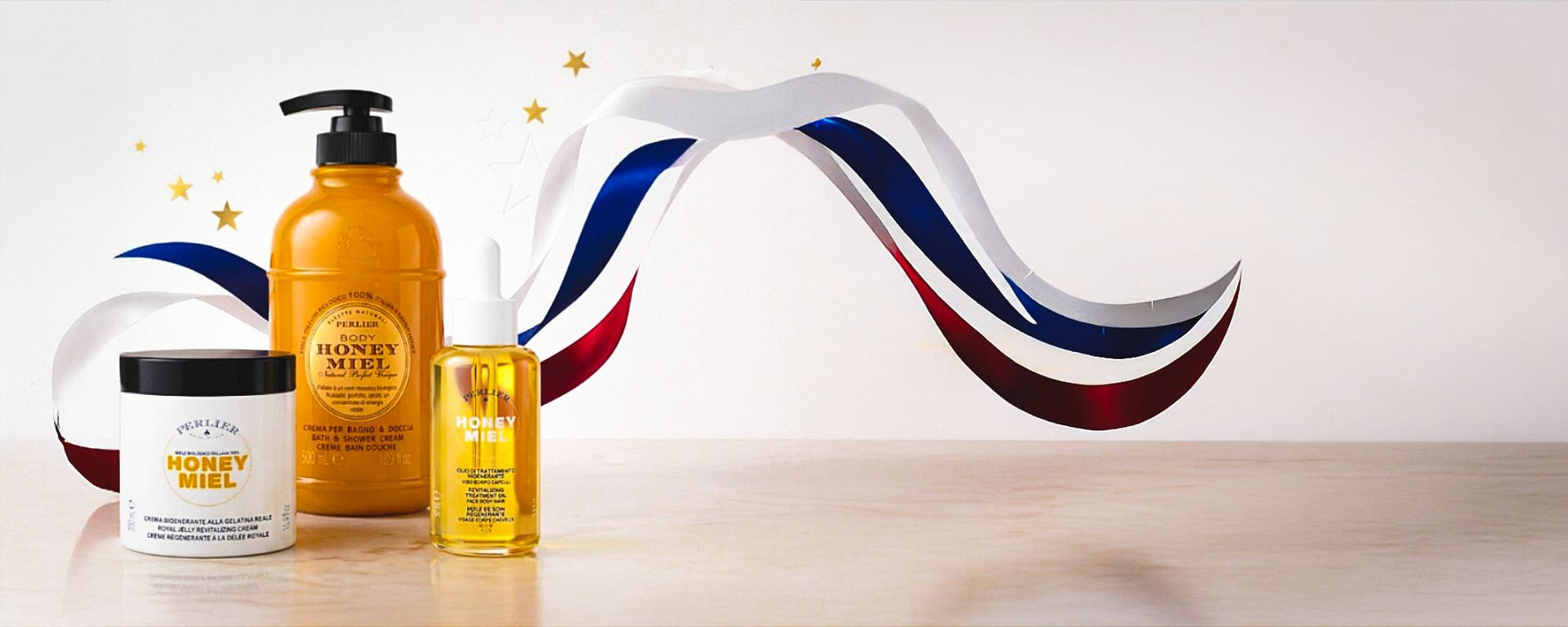 Perlier Honey Miel products on white backtround surrounded by red, white and blue ribbons