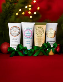 Four Perlier hand creams on a red background with Christmas decorations.