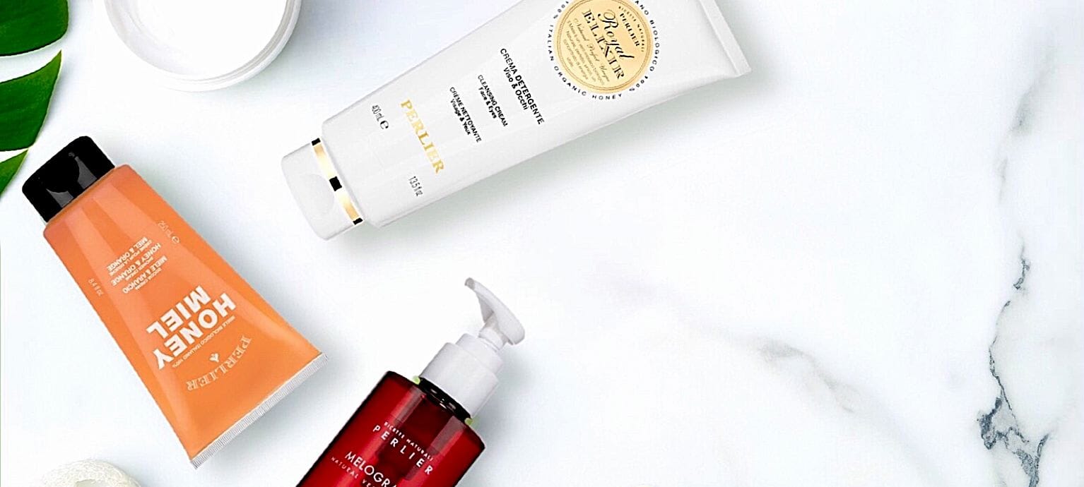 Various Perlier skin and body care products on a marble surface