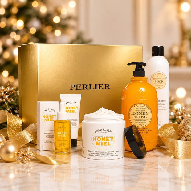 Perlier 5-pc Honey Miel gift set - body wash, hand cream, body oil, body cream and shampoo with gold gift box table in front of decorated holiday tree.