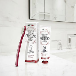 Pasta del Capitano Original Recipe toothpaste and a red toothbrush on a bathroom counter.