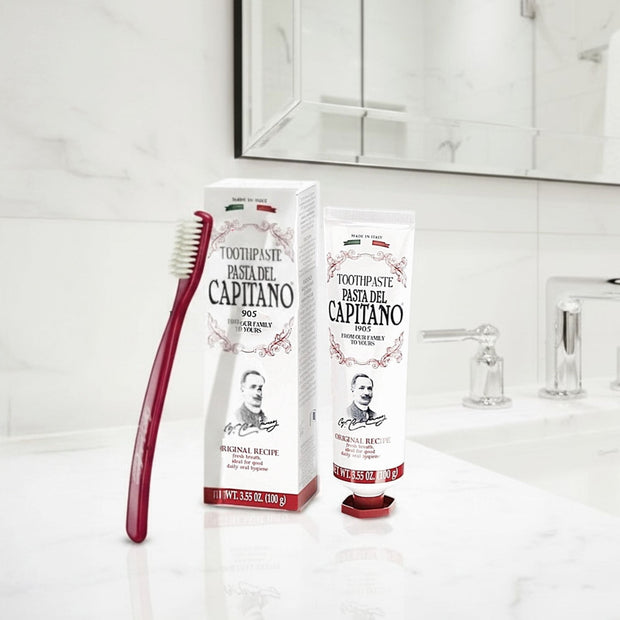 Pasta del Capitano Original Recipe toothpaste and a red toothbrush on a bathroom counter.