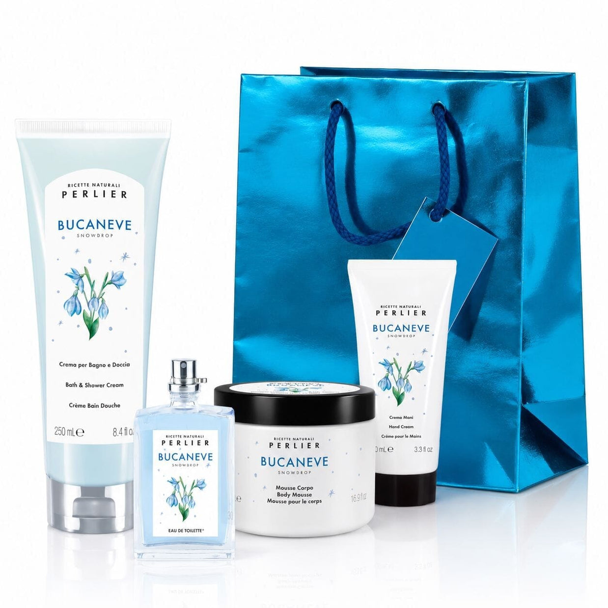 Perlier Snowdrop body care gift set featuring a bath & shower cream, body mousse, hand cream and perfume arranged in front of a metallic blue gift bag on a white background.