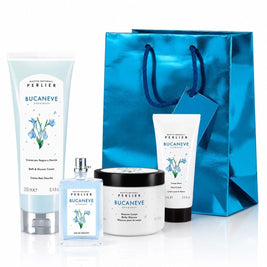 Perlier Snowdrop body care gift set featuring a bath & shower cream, body mousse, hand cream and perfume arranged in front of a metallic blue gift bag on a white background.
