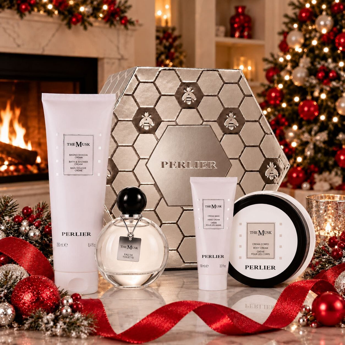 A holiday gift set from Perlier featuring The Musk products including a body wash, hand cream, body cream, and perfume arranged with a silver Perlier gift box and festive holiday decorations in front of a cozy fireplace.