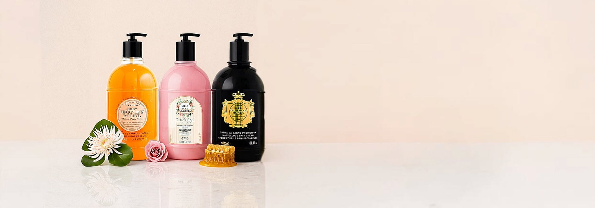 Three 3-liter bottles of Perlier honey body wash in various scents with decorative elements on a light background