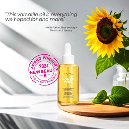 Honey Miel body oil bottle with sunflower and green leaves on a white background, featuring an award badge.