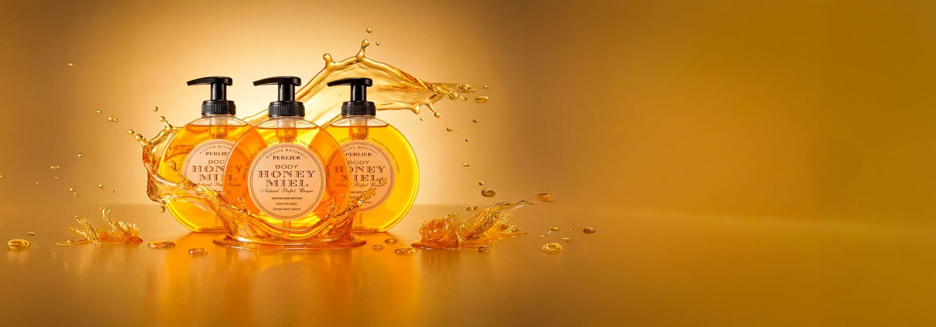 Three bottles of Perlier Honey Miel Liquid Soap with honey splashes on a golden background