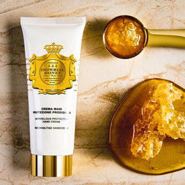 Tube of Imperial Honey hand cream with honeycomb and honey on a stone surface