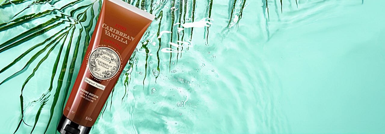 Tube of Perlier Caribbean Vanilla shower gel with palm leaves and water in the background