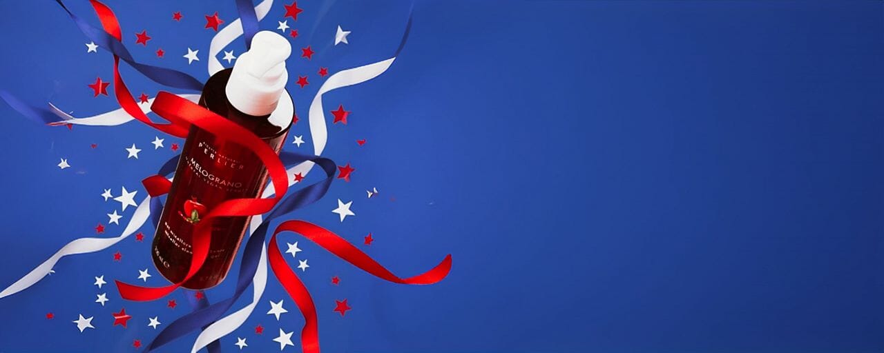 Bottle of Perlier Pomegranate Micellar Gel Cleanser surrounded by red, white, and blue ribbons on a blue background