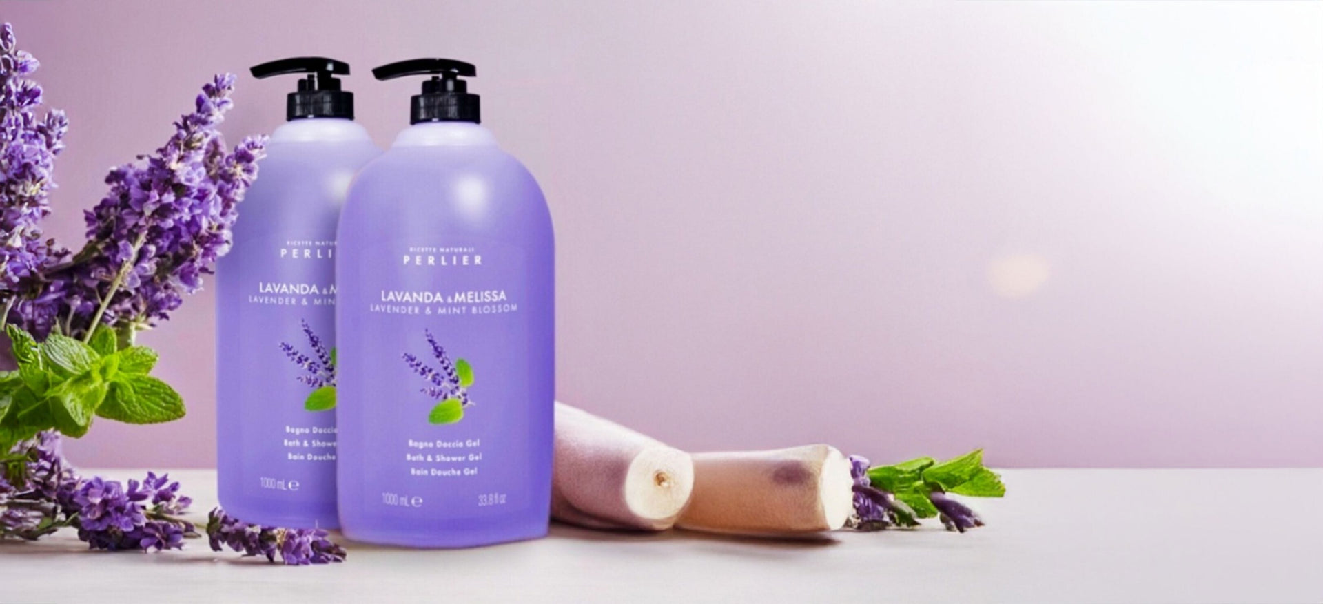 2 1 liter bottles of Perier lavender and mint shower gels on light purple background next to lavender sprigs