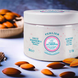 Perlier White Almond body balm jar with almonds around on a light background